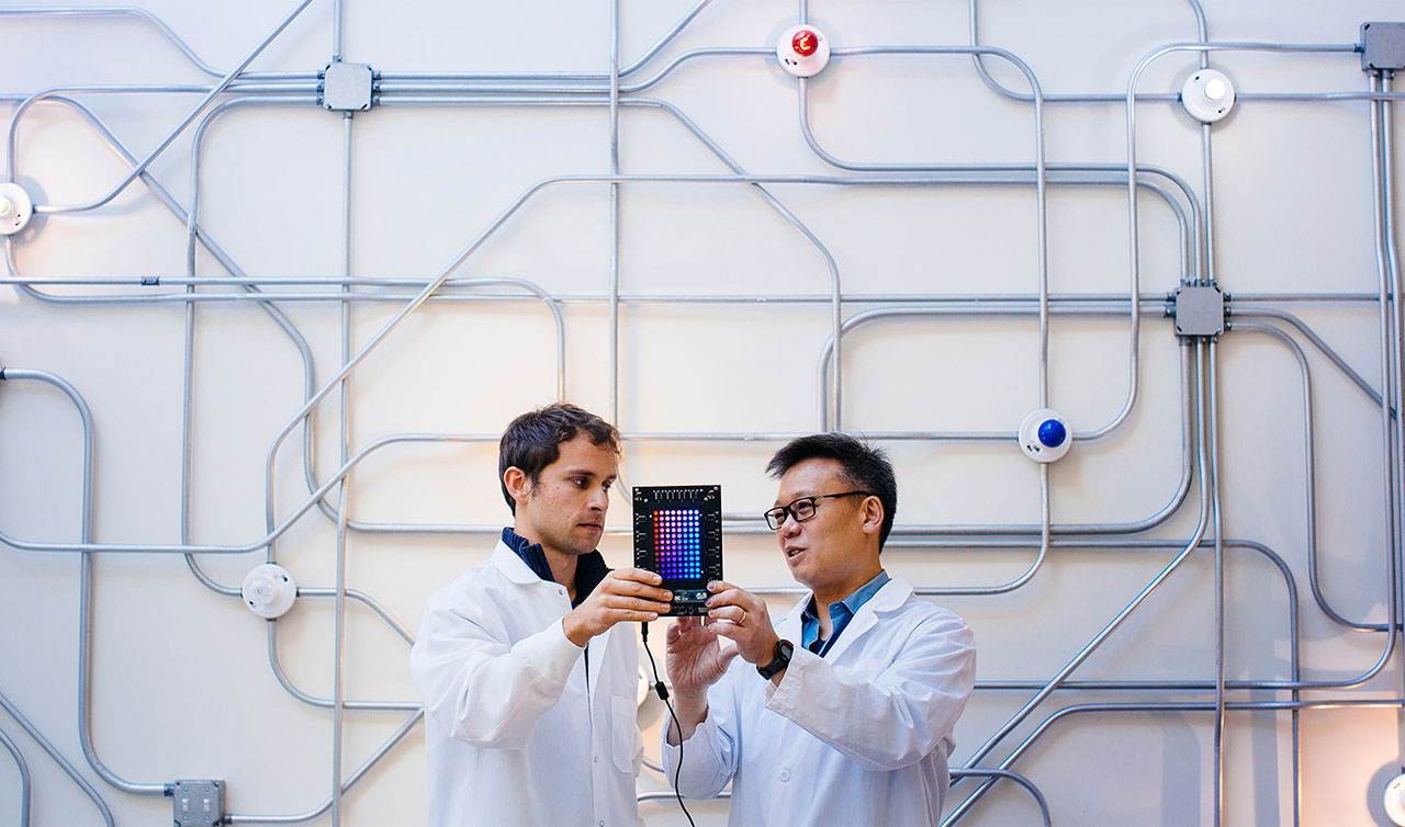 Wendell Lim and a lab member look at some machinery. 