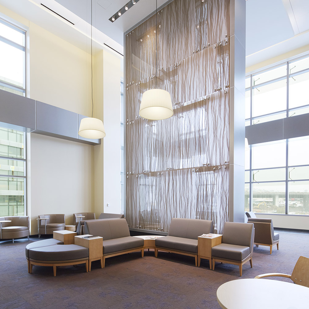 A spacious, sunlit lobby with high ceilings and low lying chairs