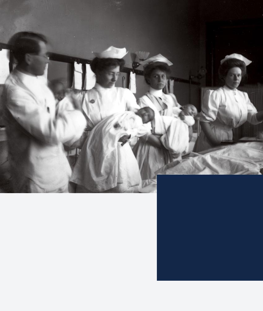 Nurses in 1908 hold babies in the nursery.