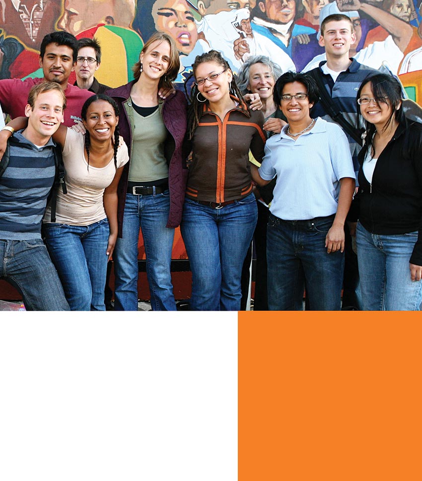 A group of students stand in front of a colorful mural.