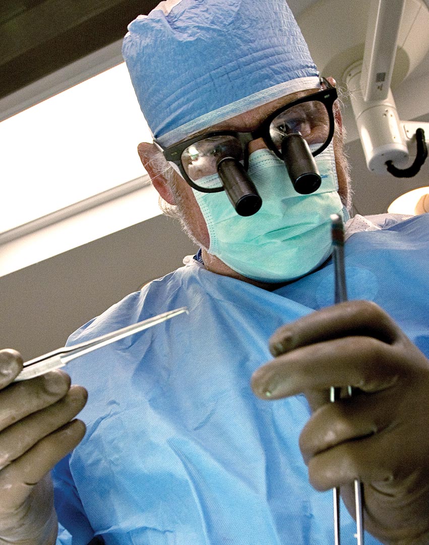 A surgeon holds up surgical instruments.