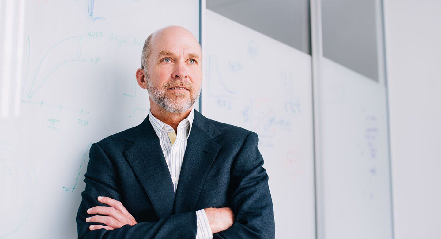 Grae Davis leans against a white board with his arms crossed.