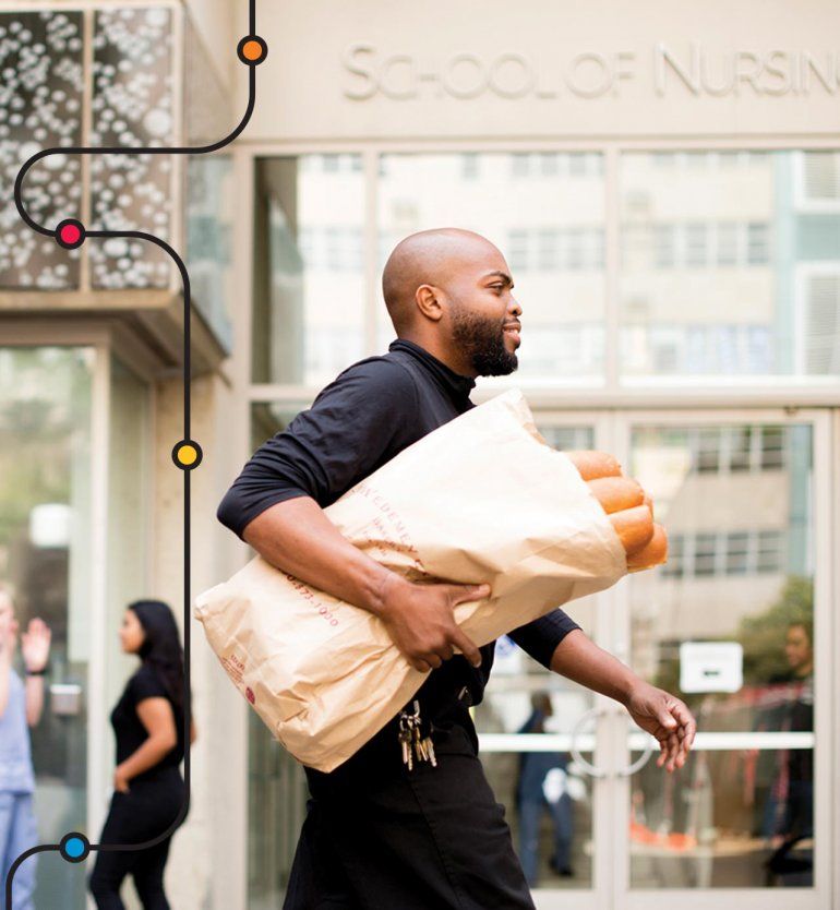 Bernardo Newson carries a large bag of baguettes past the UCSF School of Nursing.