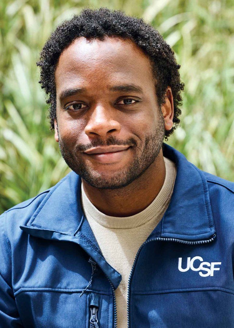 Andre Codner smiles and wears a navy jacket with "UCSF” embroidered on the chest.