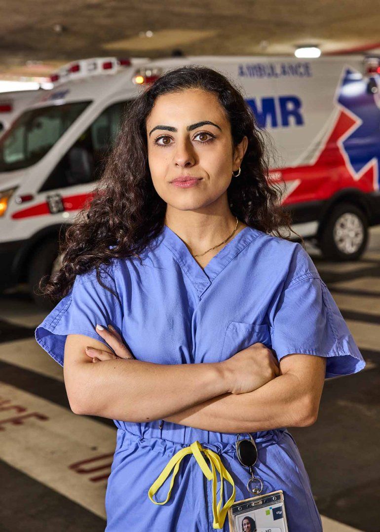 Katrin Jaradeh stands with her arms crossed, wearing blue scrubs in the ambulatory bay at UCSF’s Helen Diller Medical Center at Parnassus Heights.