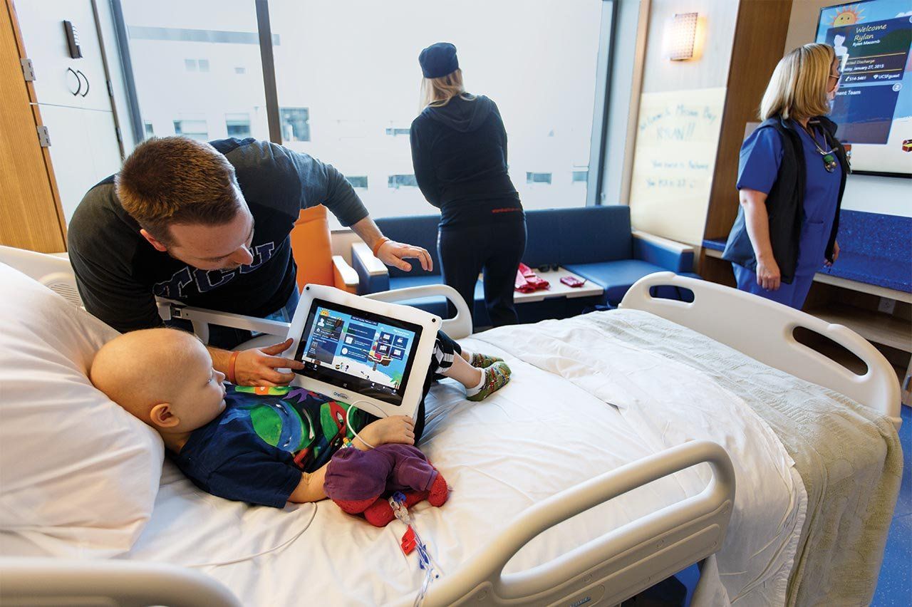 Rylan, a young hospital patient, plays video games with his dad in his new hospital room.