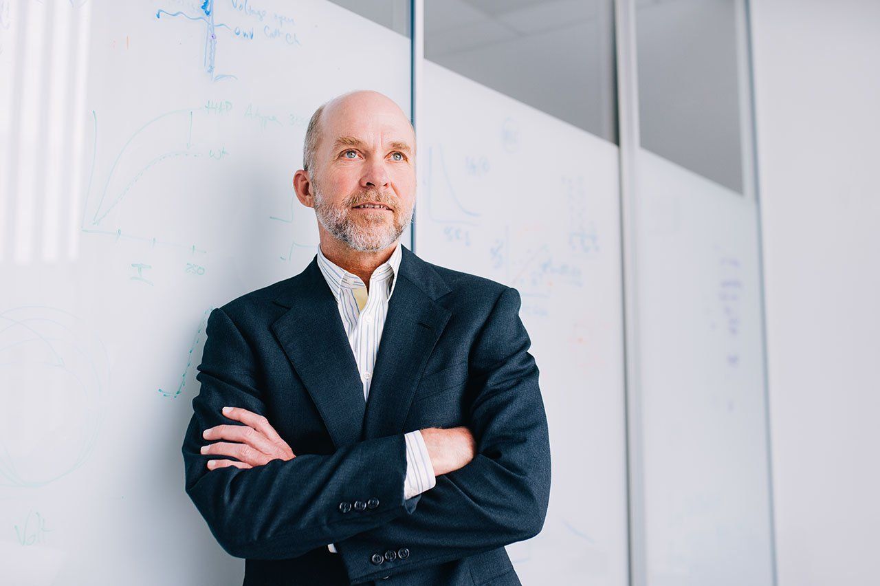 Grae Davis leans against a white board with his arms crossed.