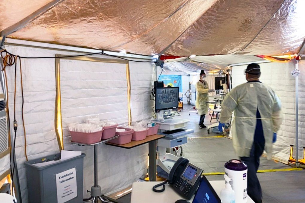 Inside a COVID-19 tent, as staff walk by.