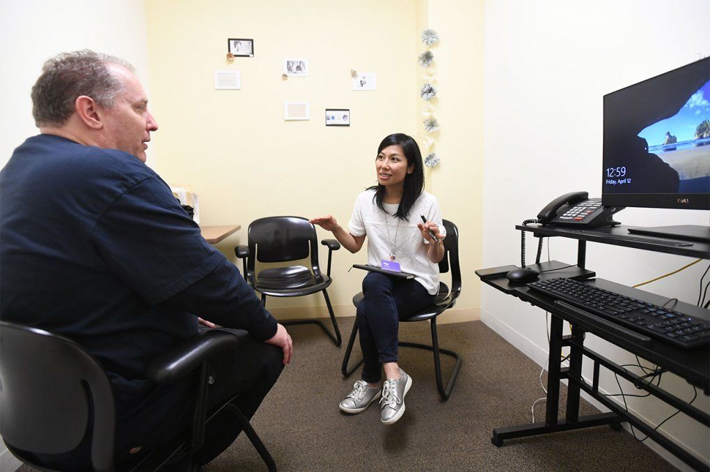 Photo of Fumi Mitsuishi speaking to a patient in a room with a tv screen.