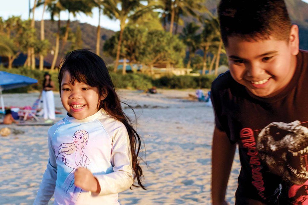 Five year old Elianna runs on the beach with her older brother
