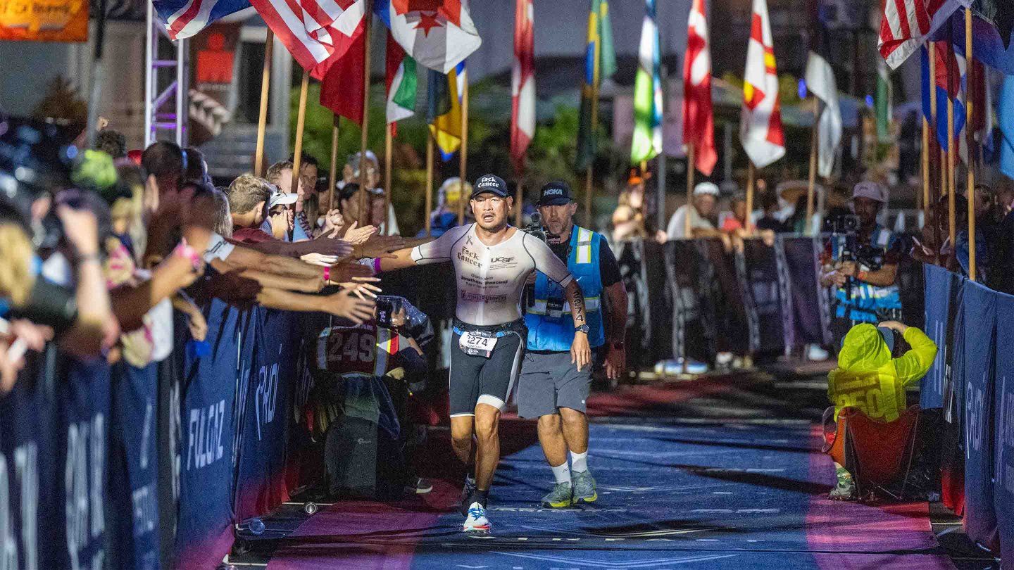 Jonathan Pascual runs down a carpeted path lined with world flags, giving high-fives to people cheering along the way.
