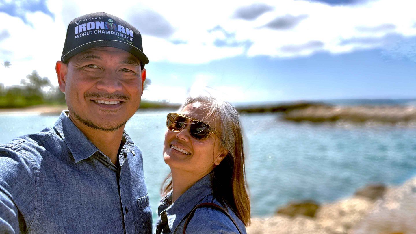 Jonathan Pascual and his wife take a selfie in front a body of water.