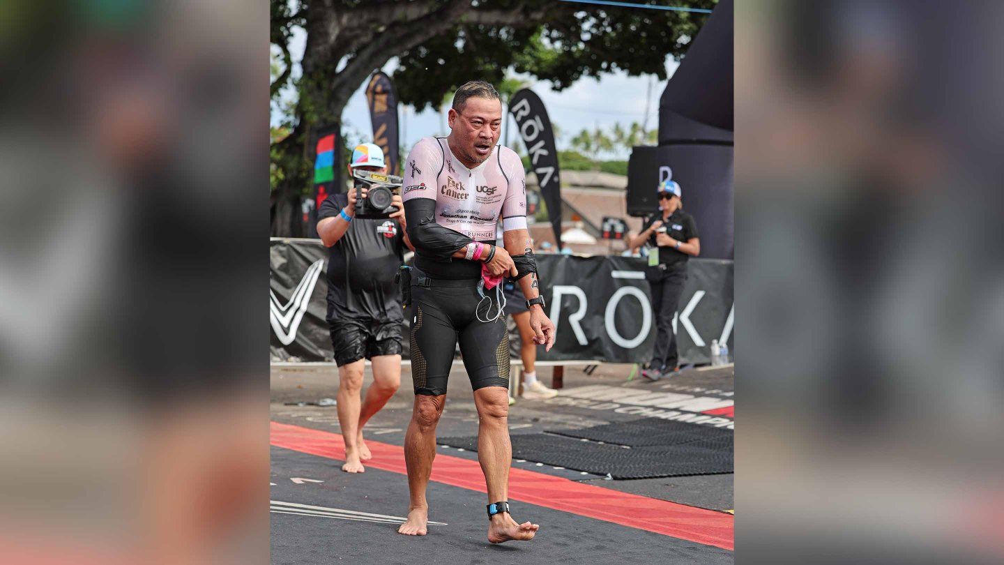 Jonathan Pascual walks out from the swim portion of the Ironman race with an expression of exhaustion and his face swollen.