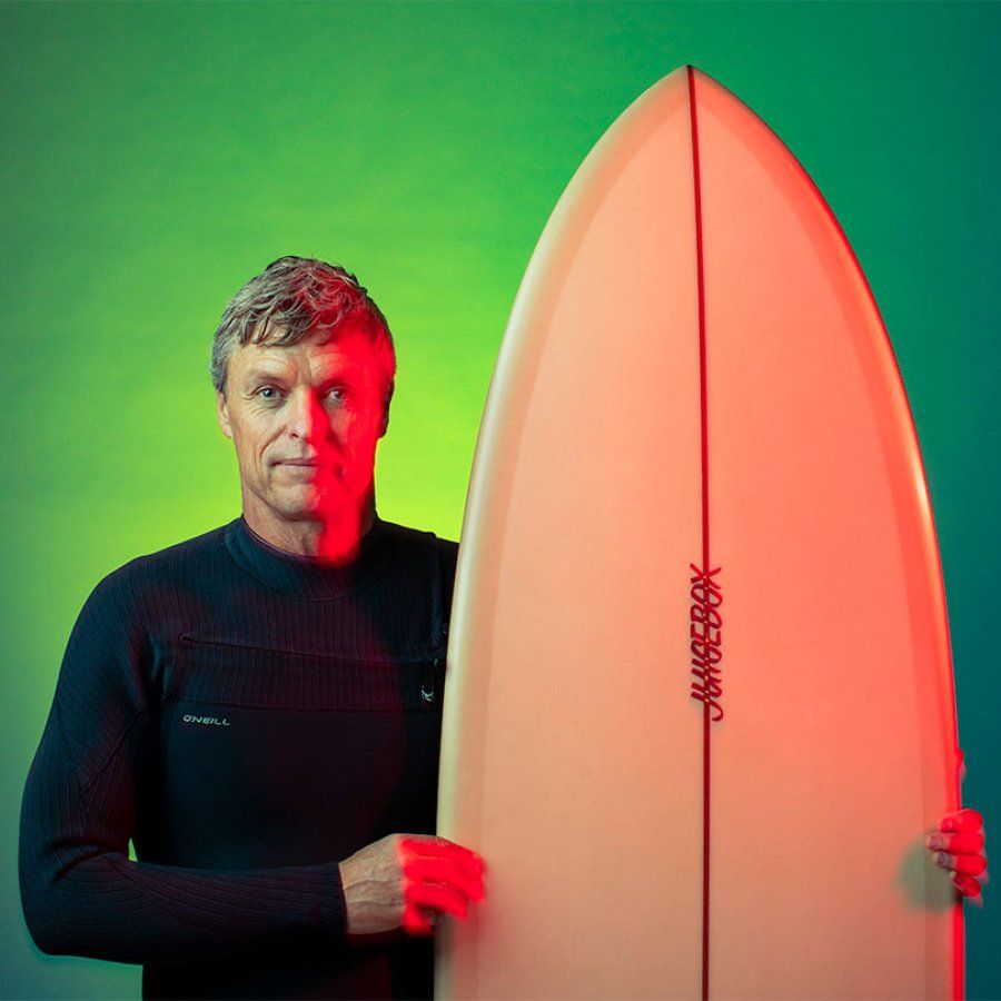 Thane Schultz stands with his surfboard.