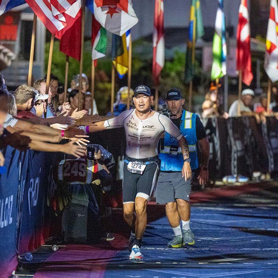 Jonathan Pascual runs down a carpeted path lined with world flags, giving high-fives to people cheering along the way.