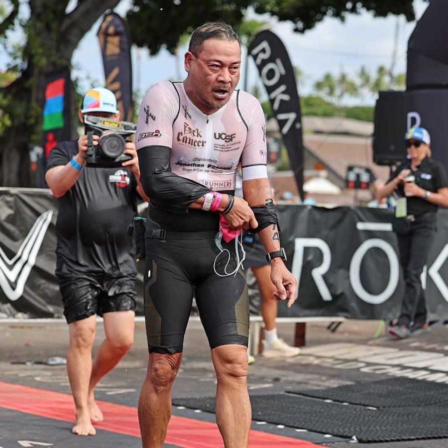 Jonathan Pascual walks out from the swim portion of the Ironman race with an expression of exhaustion and his face swollen.