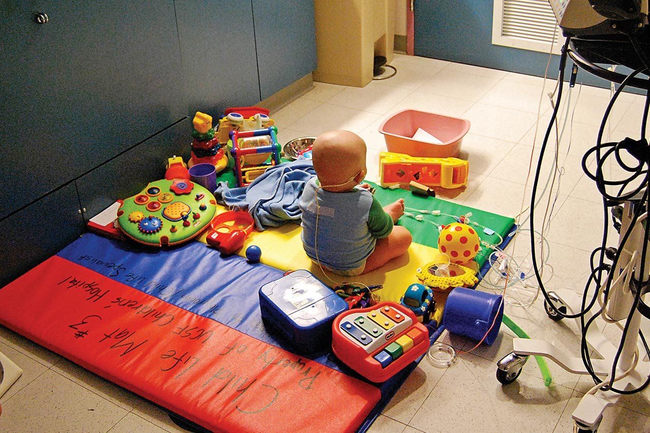 Harry Drake as a toddler on a play mat with toys while receiving chemotherapy.