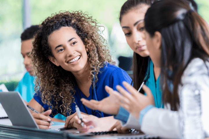 Woman leaning over to talk with classmates.