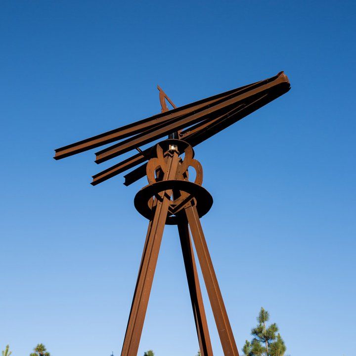 The dreamcatcher sculpture angles its arrow toward a blue sky