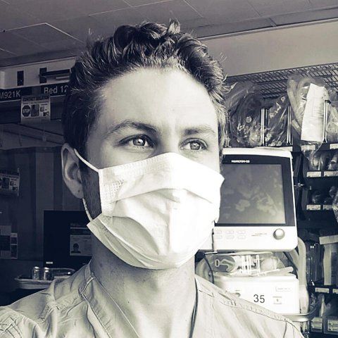 Portrait of Max Rausch in scrubs and a face mask at the hospital.