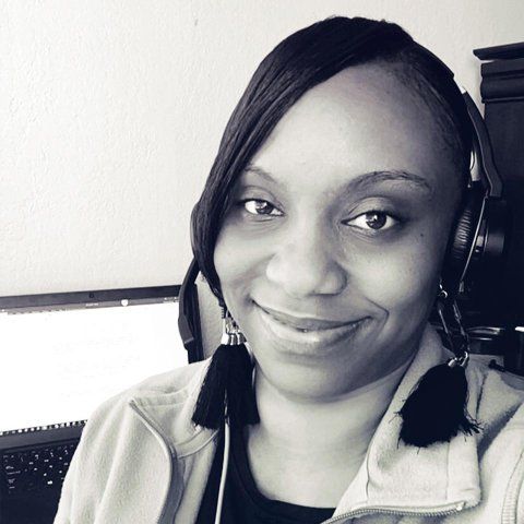 Portrait of Monique Posey with her headset on and computer in the background.