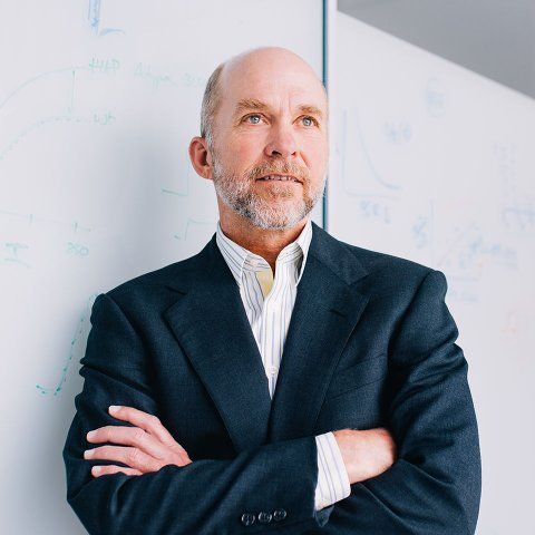Grae Davis leans against a white board with his arms crossed.