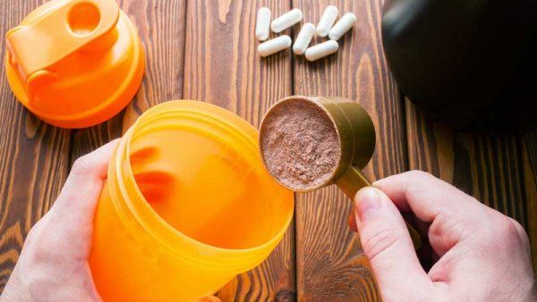 hands putting powder into shaker bottle. 