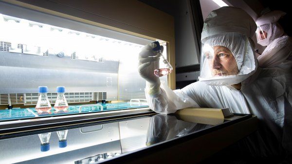 researcher in full-body protectionholds a sample in a lab