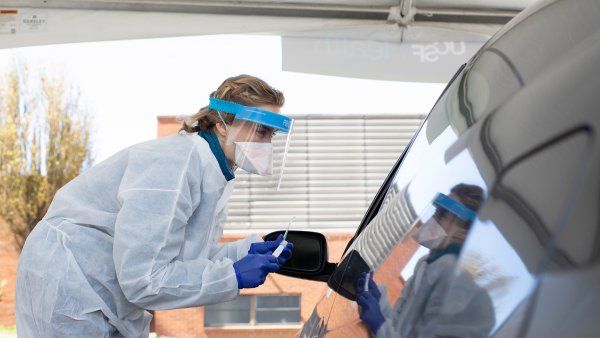 nurse tests person at drive-through testing site