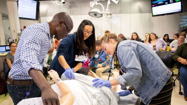 Nursing students working on mannequin of pregnant patient