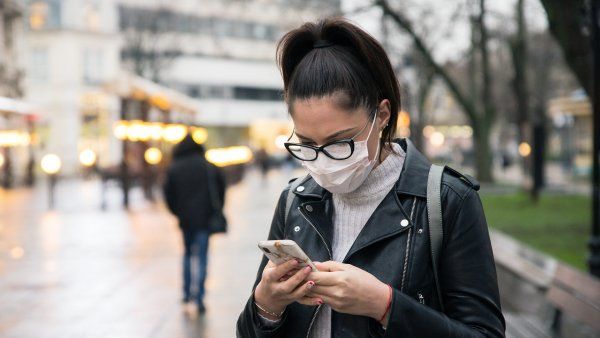 woman wearing a mask and looking at a cellphone