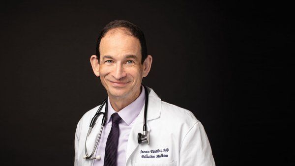 Photo of Steven Pantilat, MD, in a white doctor’s coat with a stethoscope draped around his neck, in front a black background.