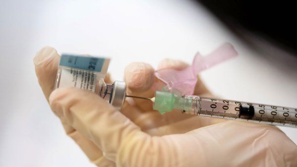 A hand holding a syringe and vial