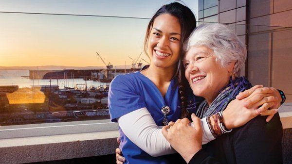 Mei-Ling Fong and Peggy Cadbury look over a sunrise with their arms wrapped around each other.