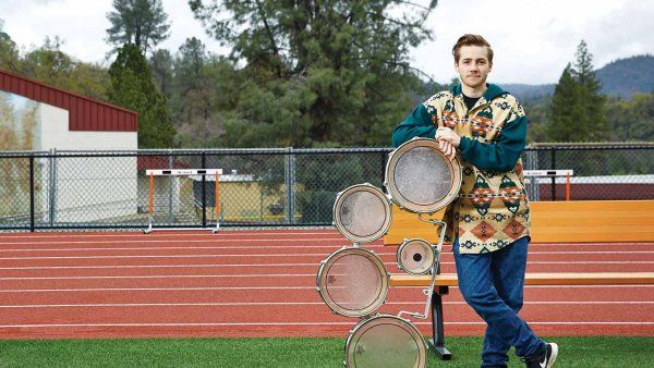 Oliver Bishop with drumline equipment at his high school track field. 