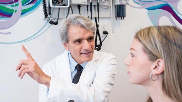 Dr. Stephen Hauser, examining a patient, gestures for her to look straight ahead.