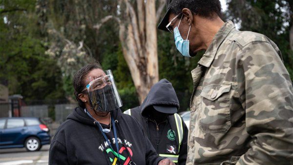 Photo of Kim Rhoads in a face mask and face shield talking to a man at a vaccine clinic.