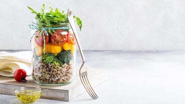Homemade salad in glass jar with quinoa and vegetables.
