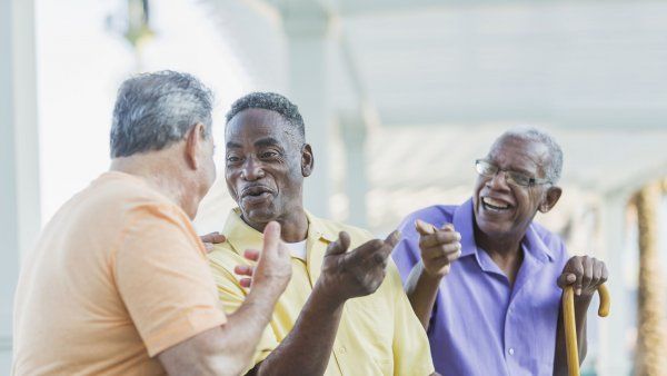 three elderly men talk while sitting