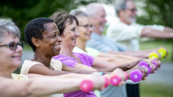 diverse group of elderly people exercising outside with weights