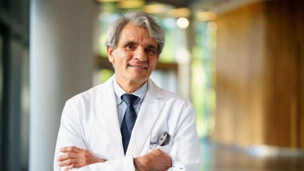 Stephen Hauser, MD, posing for a portrait in a white doctor's coat