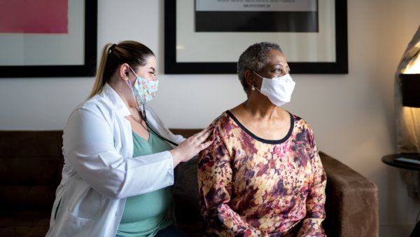 A doctor listens to a woman's back with a stethoscope