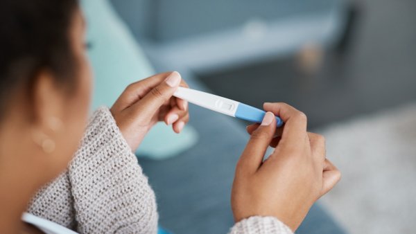 An unrecognizable woman looks down at a pregnancy test