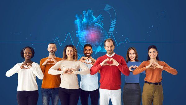 A group of people make heart signs with their hands while standing in front of a digital heart