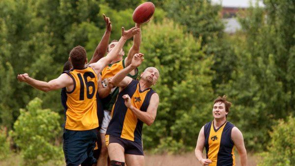 A group of male athelets playing Australian Rules Football.