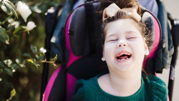 Seven-year-old Hannah Detlefsen smiles as she sits in her wheelchair. Gould Syndrome has caused her physical and cognitive delays, but she has become more expressive over time.
