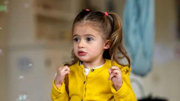 A two-year-old girl named Emiliana looks on as bubbles float through her home.