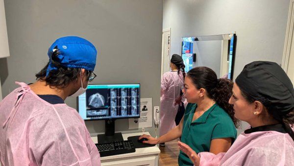 three dental students in office look over x rays.