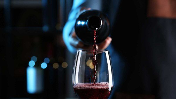 Wine is poured into a wine glass from a bottle amongst a dark backdrop.