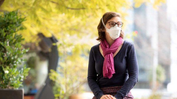 Epidemiologist Alison Cohen wears a face mask while sitting outdoors to protect from respiratory infections.